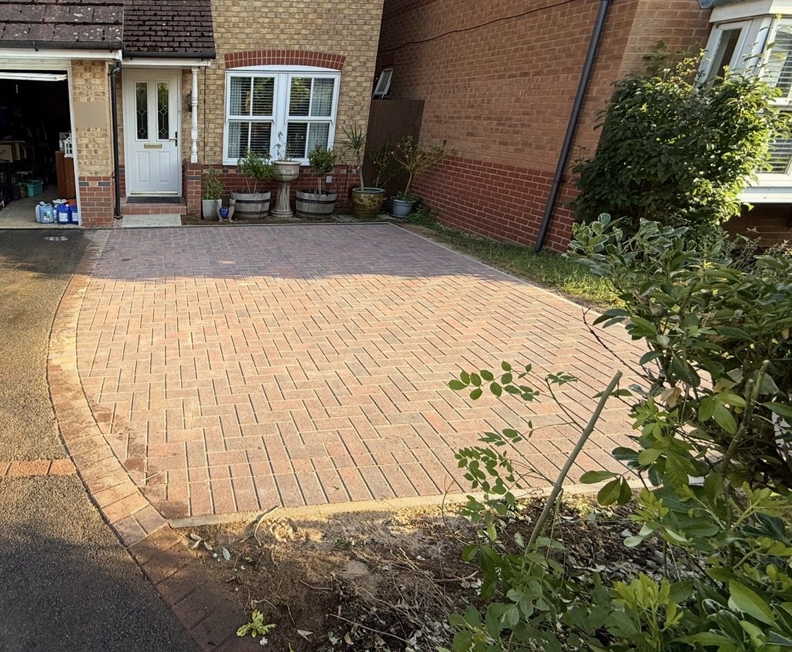 Red brindle herringbone block parking bay beside a tarmac drive in front of a house in Oakham Red brindle herringbone block parking bay beside a tarmac drive in front of a house in Oakham