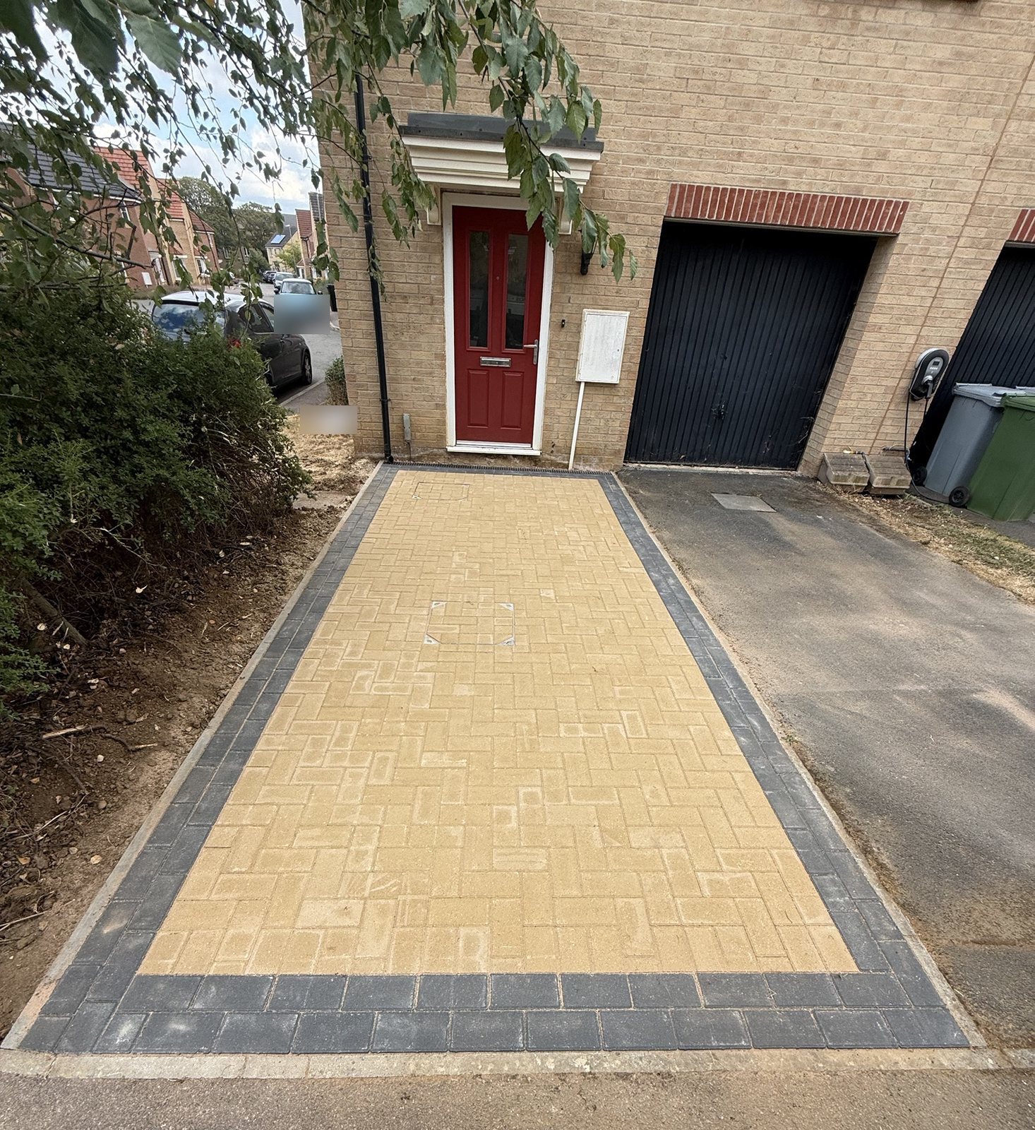 Buff herringbone block paving with a charcoal double border leading to a red front door in Oakham Buff herringbone block paving with a charcoal double border leading to a red front door in Oakham