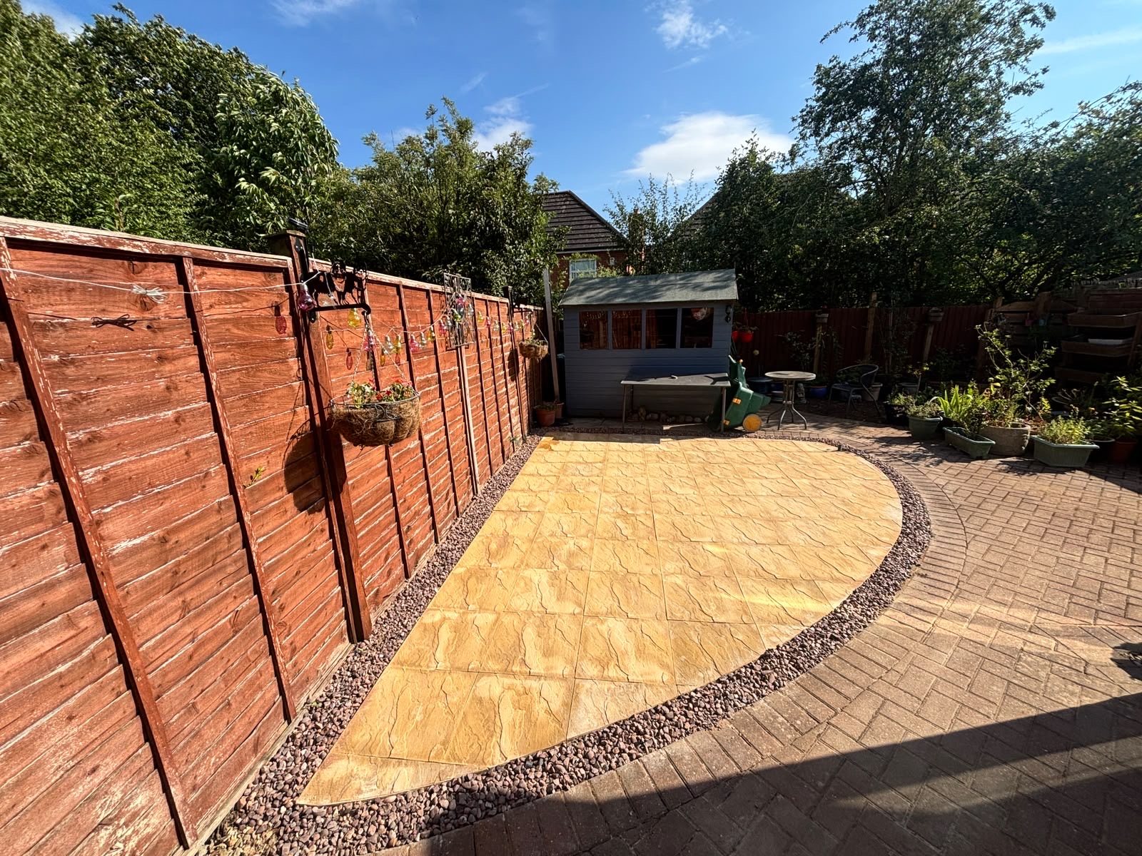 Buff riven-effect patio with a curved edge and plum chipping border set into block paving in an Oakham garden Buff riven-effect patio with a curved edge and plum chipping border set into block paving in an Oakham garden