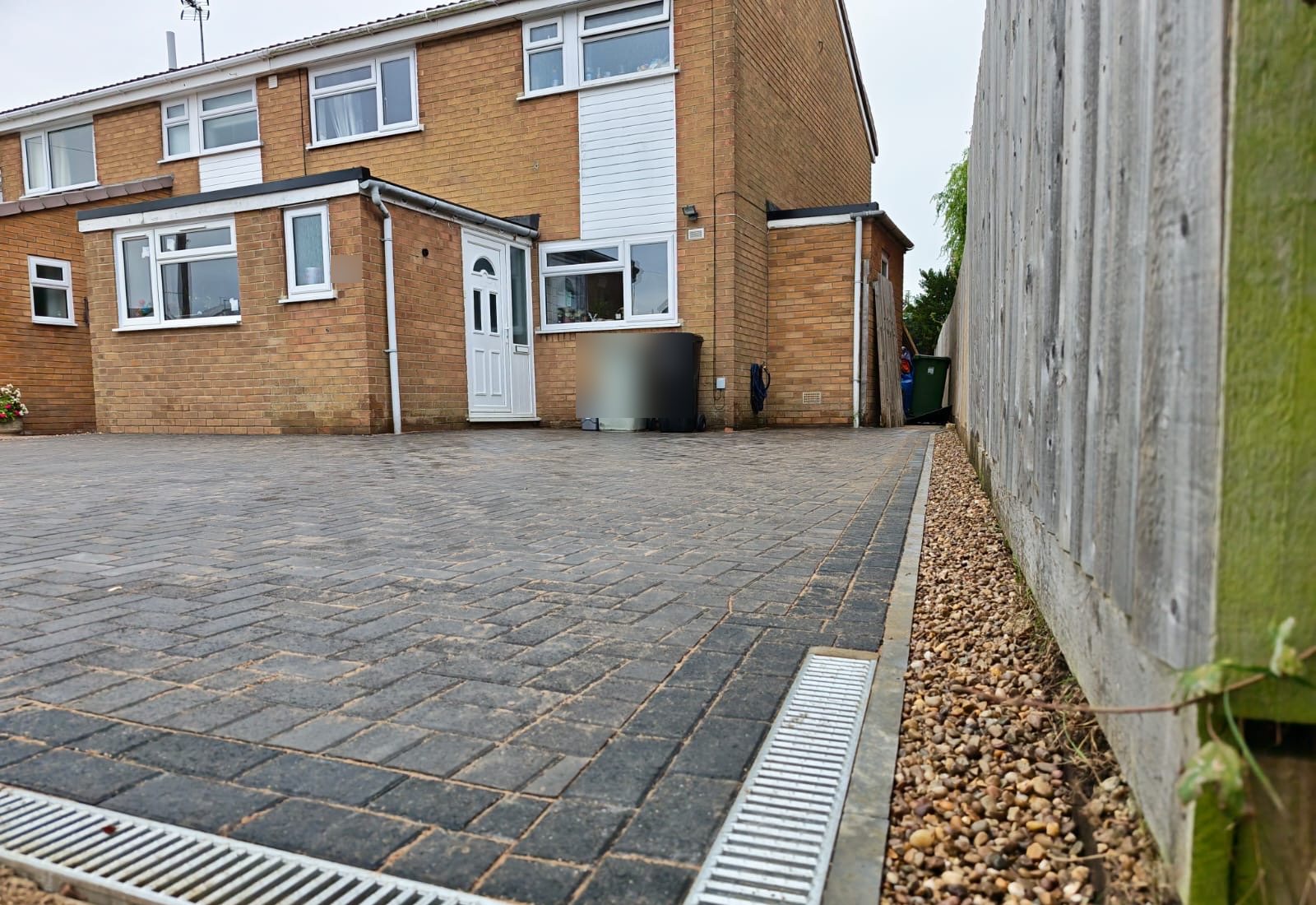 Channel drains meeting at the front corner, with the gravel strip along the fence Channel drains meeting at the front corner, with the gravel strip along the fence