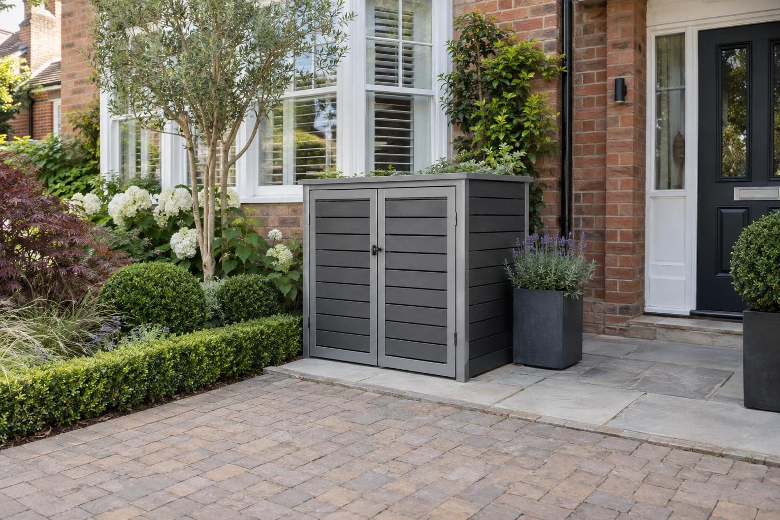 Grey composite wheelie bin store on a paved pad beside a block paved driveway Grey composite wheelie bin store on a paved pad beside a block paved driveway