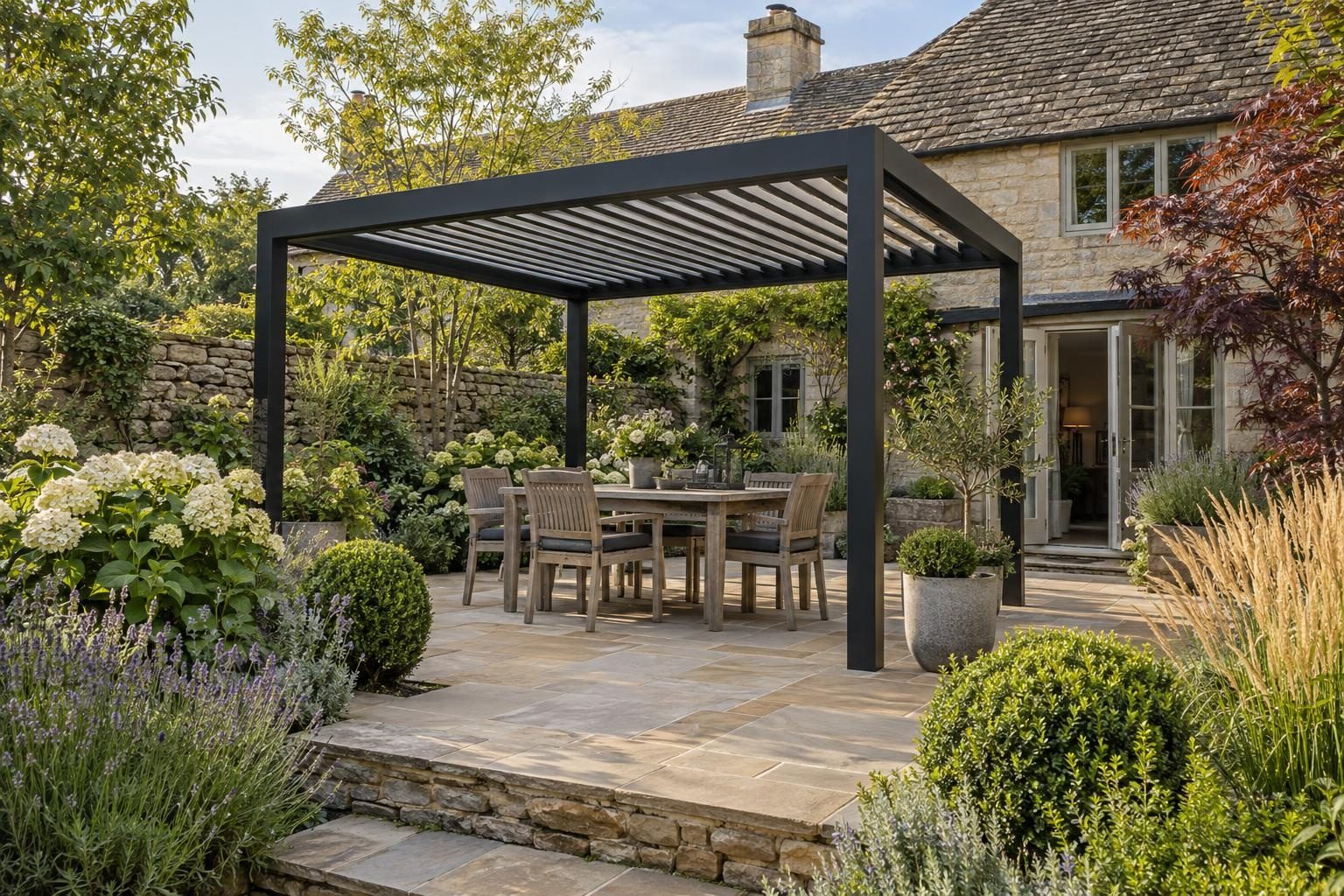 Black louvred pergola over a dining table on a sandstone terrace at a stone cottage Black louvred pergola over a dining table on a sandstone terrace at a stone cottage