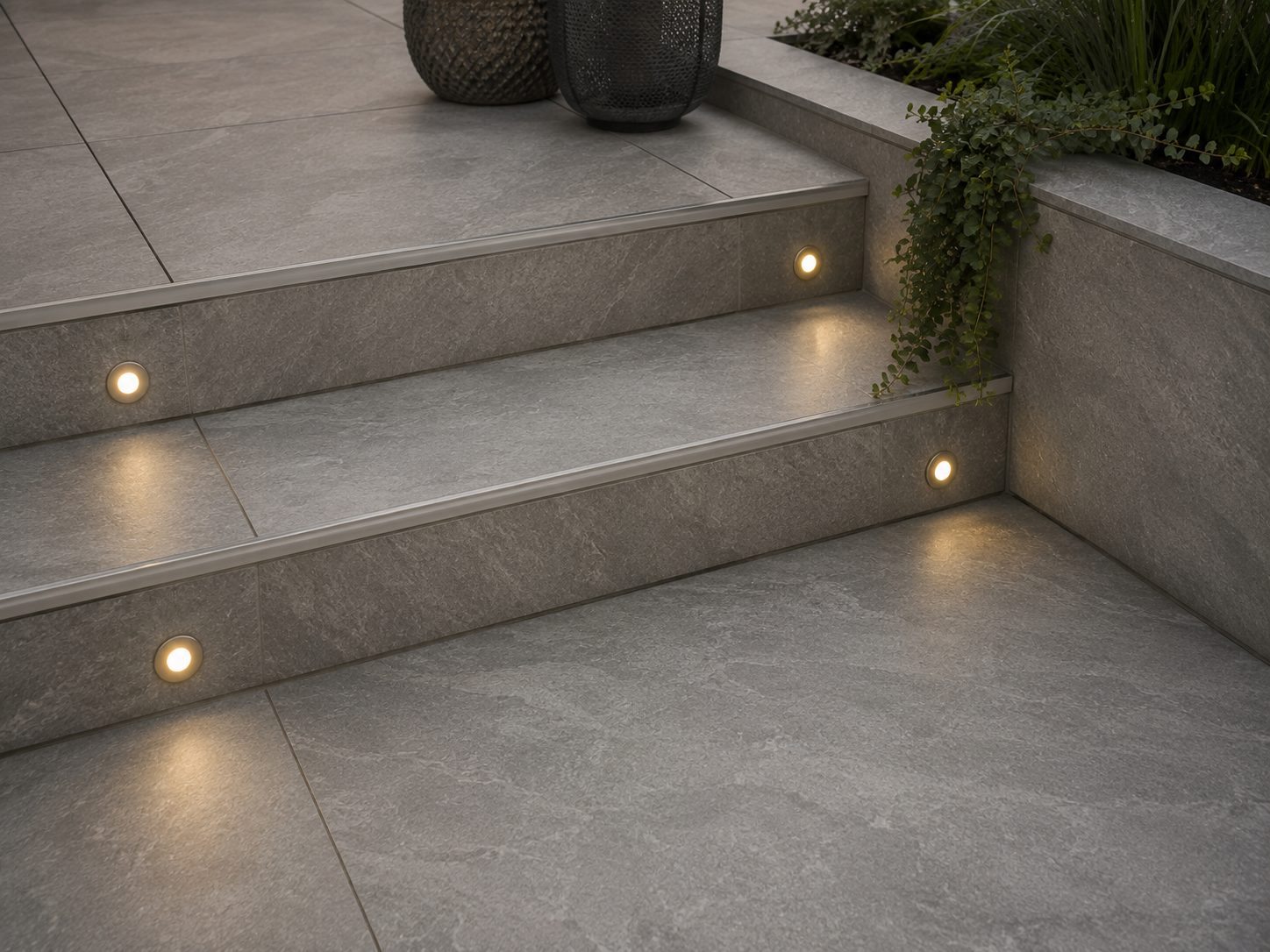 Grey porcelain patio steps with recessed riser lighting in a Rutland garden