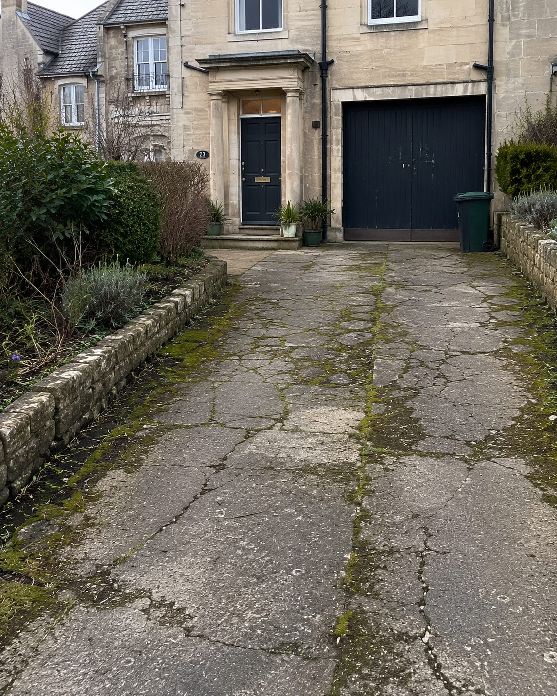 Before: cracked and weathered old paving at a stone house awaiting a new driveway