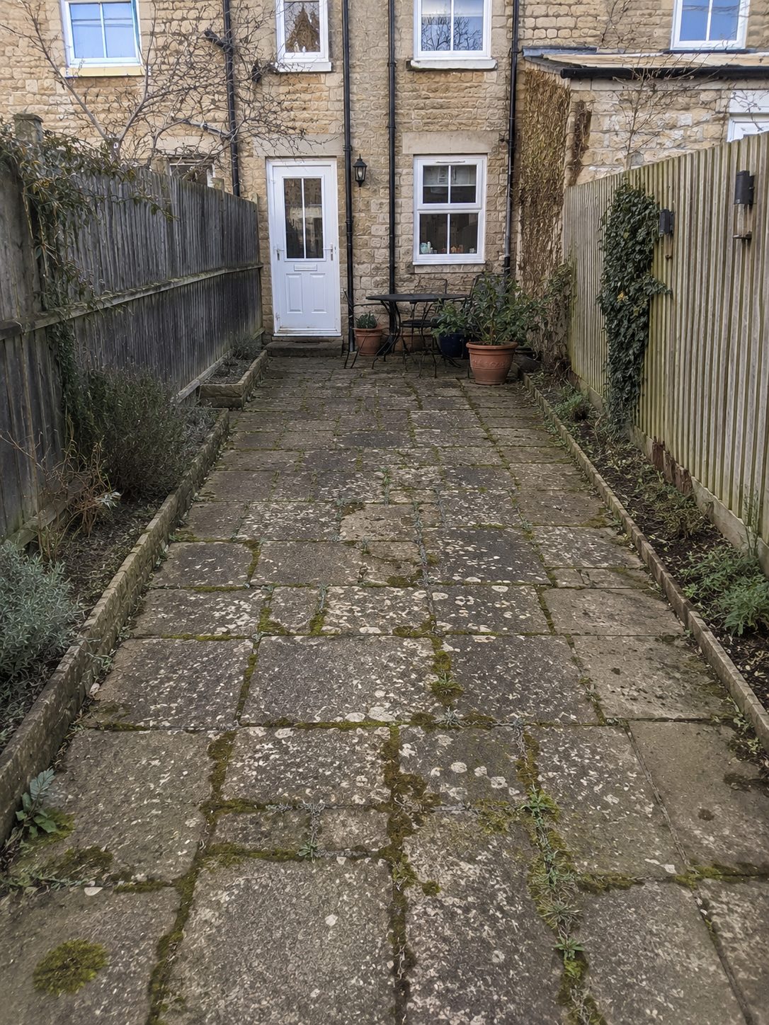 Before: a narrow side return with mossy, weathered paving awaiting transformation